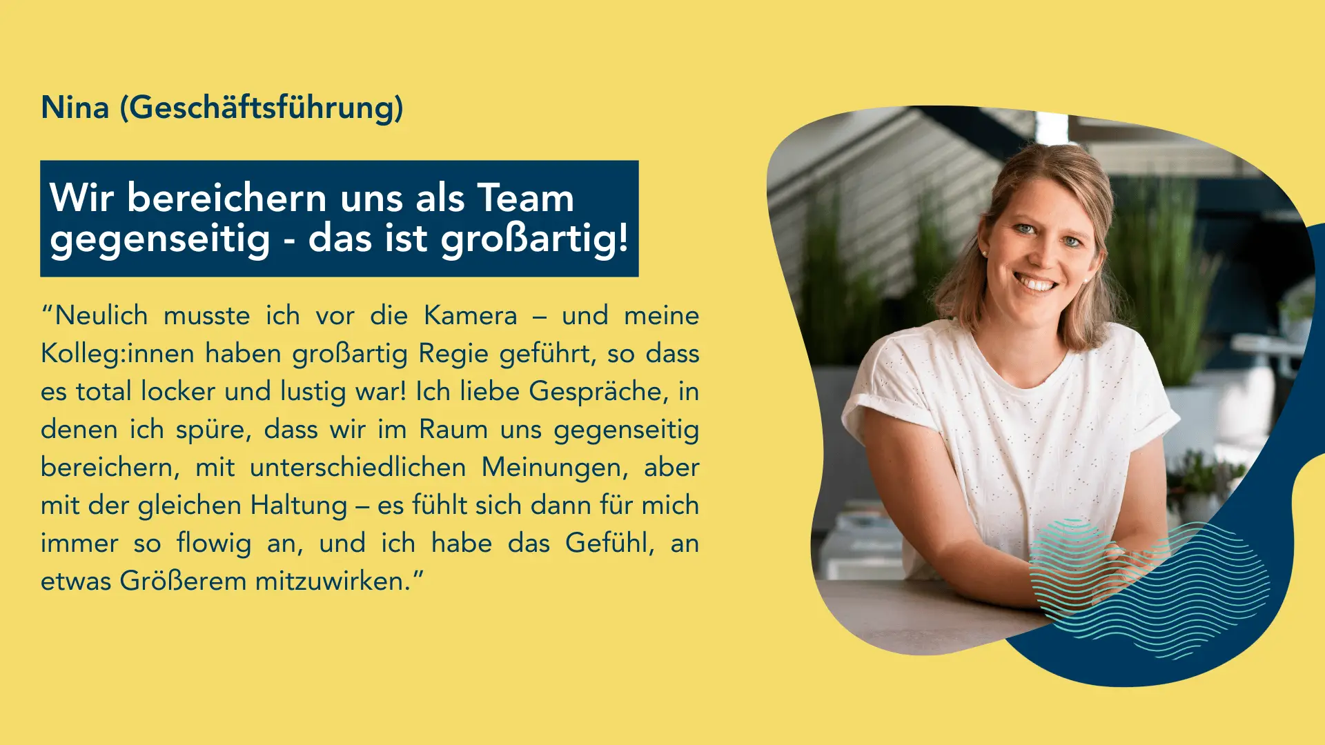 Person in einem weißen T-Shirt sitzt an einem Tisch in einem modernen, hellen Raum mit Pflanzen im Hintergrund.